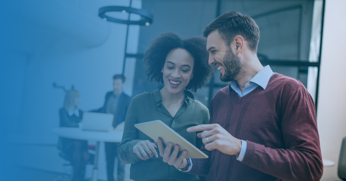 two people smiling while looking at a tablet